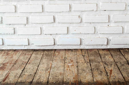 The plank floor behind a white brick wall.