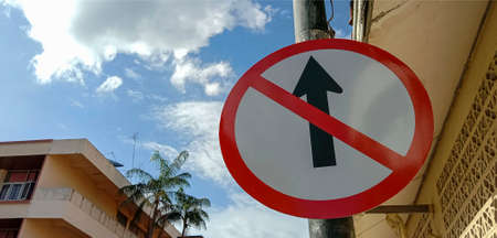 The electric pole has a warning sign forbidding the car to go straight.
