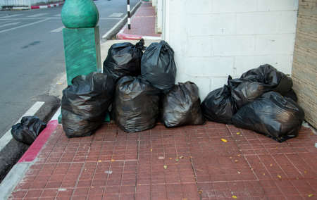 Several black bags of garbage were placed on the sidewalk.の写真素材