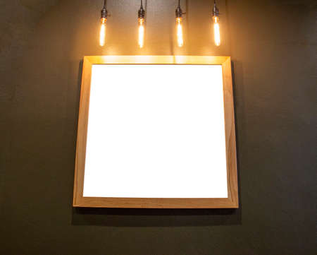 White wooden photo frame with a small long lamp in the dark.の写真素材