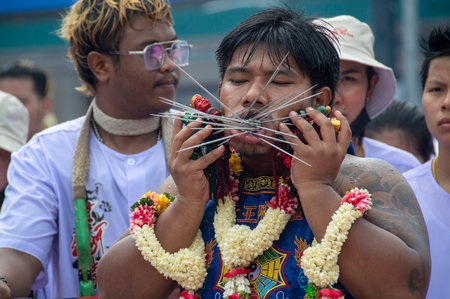 Phuket, Thailand 10-2-2022 The male figure uses a spike to pierce through the mouth of several...