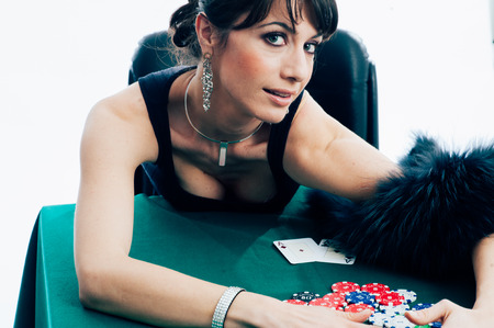 Young caucasian brunette playing poker at the green table. Studio shotの写真素材
