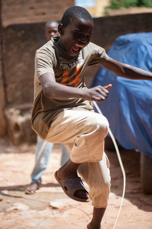 Mali, Africa - circa August 2009 - Black african young boy happy starting a wood game living in a rural area near Bamakoのeditorial素材