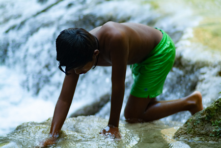 Latin boy having fun getting a bath in the middle of October on a turquoise water river. Global warming affects water temperature. SentierElsa, Colle Val dElsa. Tuscany Italy Europeの写真素材