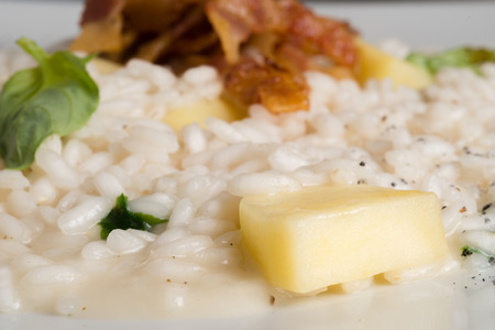risotto with bacon apple and basil on a white dishの写真素材