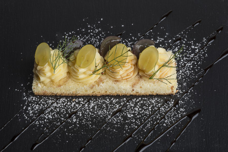 soft pie with custard and grapes on slate square dishの写真素材
