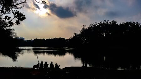 Sunset over the lake with people and a dog sillhouettes | Sunset over the lake with people and a dog...