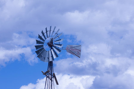 windmill with partly cloudy skies on a ranch on a warm summer day.の写真素材