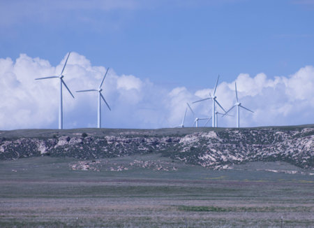 Alternative energy wind farm in wide open flatland, on a partly cloudy summer day, with wind turbines in view.の写真素材