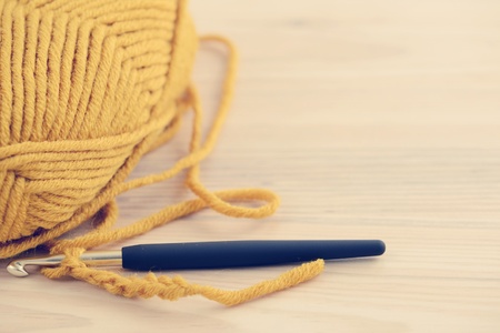 crocheting with wool ball and crocheting hook. wooden table background