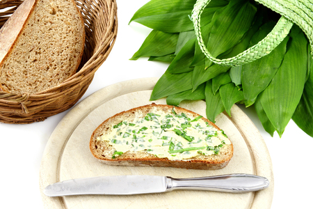 bunch of wild garlic (ramson) and bread slice with ramson butter and antique silverware on isolated...