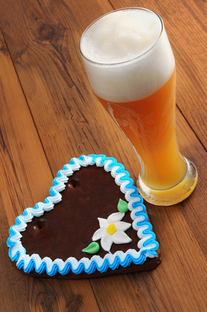 Oktoberfest gingerbread heart cookie with copy space and weissbier glass on wooden backgroundの写真素材