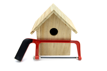 Building bird nesting box with nails and saw. bird looking out of nestbox. white isolated backgroundの写真素材