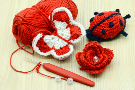 crocheting red white butterfly as well as rose and lady bug with crochet hook and woolの写真素材