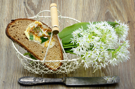 Bunch of ramson wild garlic flower heads and leaves on basket with fresh bread and ramson butter....