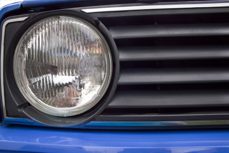 close up of old blue automobile headlight and grilleの写真素材