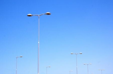 seven silver street lamps against blue skylineの写真素材