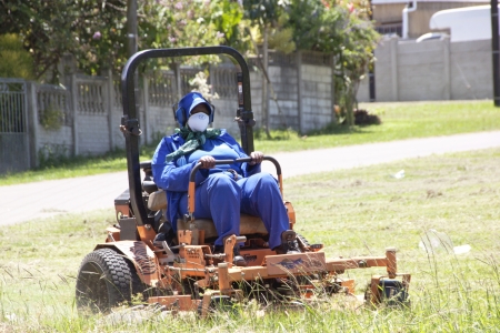 DURBAN, SOUTH AFRICA - JANUARY 23, 2014 : Unknown female municipal worker mows the grass in public park in Queensburgh Durban のeditorial素材