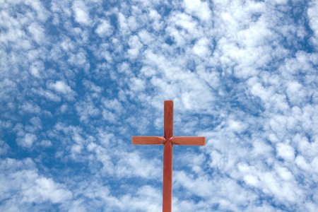 wooden cross against blue cloudy sky 