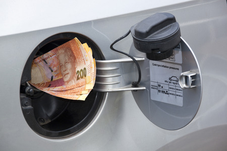 concept of south african banknotes feeding into petrol tank indicating petrol price increase
