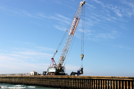 DURBAN, SOUTH AFRICA - MAY 3, 2014: Four unknown workers and mobile crane operate on site constructing new pier on North beach in Durban South Africaのeditorial素材