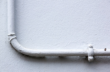 painted water pipe mounted on plastered wallの写真素材