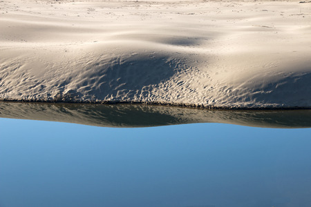 top of bank reflected in calm blue lagoon waterの写真素材