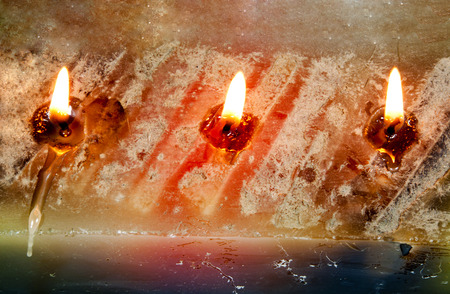 three burning wicks and molten wax on large rectangular candleの写真素材