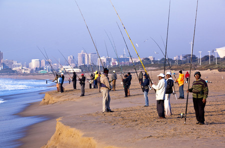 DURBAN, SOUTH AFRICA - JULY 2, 2014: Many unknown early morning fishermen fish on Blue Lagoon beach in Durban South Africaのeditorial素材