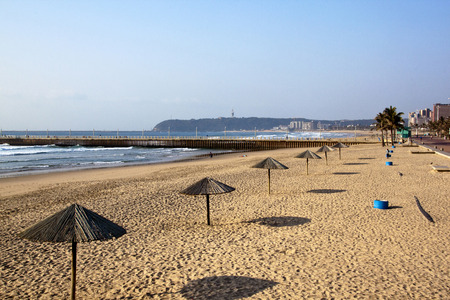 DURBAN, SOUTH AFRICA - JULY 23, 2014: Many unknown early morning walkers at North beach with row of sun shade canopies in Durban South, Africaのeditorial素材