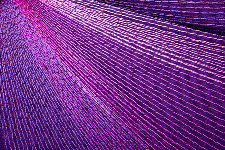 intricate colorful stitching forming pattern on mauve fabricの写真素材