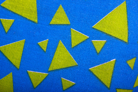 yellow fabric triangles on blue texured materialの写真素材