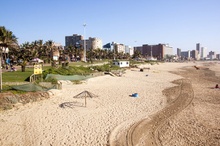 DURBAN, SOUTH AFRICA - JUNE 7, 2015: Many unknown people on beach and promenade against Durban skyline in South Africaのeditorial素材