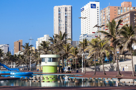 DURBAN, SOUTH AFRICA - JUNE 24, 2016: Early morning pool area against palm trees and city skyline on Golden Mile Beach front in Durban, South Africaのeditorial素材