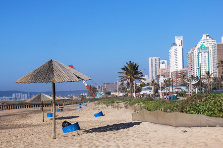 DURBAN, SOUTH AFRICA - JUNE 26, 2016: Empty beach on quiet early morning  with blue garbage bins and cranes building concrete pier and sun shade  in Durban, South Africaのeditorial素材