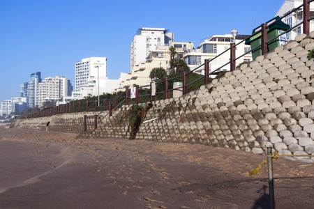 UMHLANGA, DURBAN, SOUTH AFRICA - JULY 8, 2016: Empty beach and concrete retaining wall  on early morning beach front against commercial and residential complexes in Umhlanga Rocksのeditorial素材