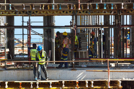 MHLANGA RIDGE, DURBAN, SOUTH AFRICA - OCTOBER 21, 2016: Close up of many unknown workers working amongst scaffolding and concrete on construction  siteのeditorial素材