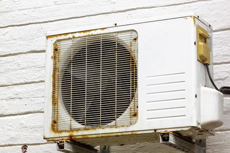 Old vintage rusting metal exterior fitted airconditioning unit mounted on wall needing maintenanceの写真素材