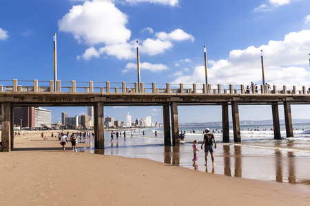 DURBAN, SOUTH AFRICA - APRIL 28, 2016: Many unknown people  enjoy morning visit to Vetchies pier on Golden Mile beachfront against city skyline in Durban, South Africaのeditorial素材
