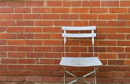 Empty outdoor chair against vintage red brick wall patterns and texture backgroundの写真素材