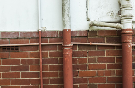 Neglected Vintage old plumbing pipes on cracked blue and red brick wall background