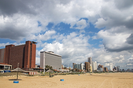 DURBAN, SOUTH AFRICA - DECEMBER 2, 2016: Empty quiet early morning Golden Mile beach front against comercial and residential buildings and blue cloudy sky in Durban, South Africaのeditorial素材