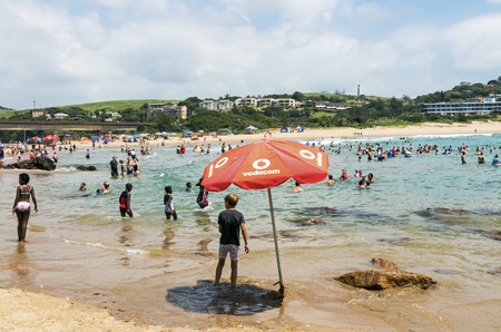 SCOTTBURGH, DURBAN, SOUTH AFRICA - DECEMBER 23, 2016: Many unknown people and colorful umbrellas on early morning  beach at Scottburgh south of Durban in South Africaのeditorial素材
