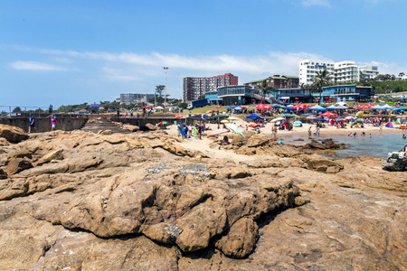 SCOTTBURGH, DURBAN, SOUTH AFRICA - DECEMBER 23, 2016: Many unknown people and colorful umbrellas on early morning  beach at Scottburgh south of Durban in South Africaのeditorial素材