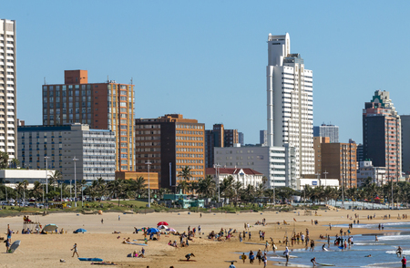DURBAN, SOUTH AFRICA - APRIL 15 , 2017: Many unknown people on early morning beach against beachfront and city skyline in Durban, South Africaのeditorial素材
