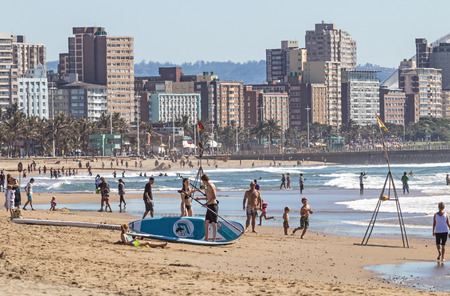DURBAN, SOUTH AFRICA ; APRIL 24, 2017: Many unknown people on morning visit to beach against Durban city skyline in South Africaのeditorial素材