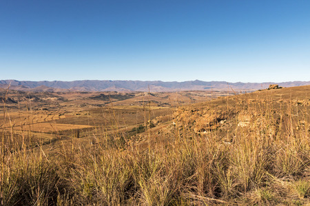 Golden cold dry winter landscape and rocky mountain against blue cloudy sky in the Orange Free State in South Africaの写真素材