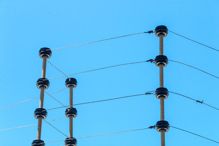 Close up wall mounted high voltage electric security fence instalation isolated against blue sky...