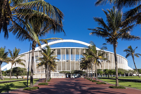 DURBAN, SOUTH AFRICA - FEBRUARY 23, 2018: Close up morning empty palm tree lined paved walkway leading towards Moses Mabhida stadium and clear blue sky in Durban, South Africaのeditorial素材