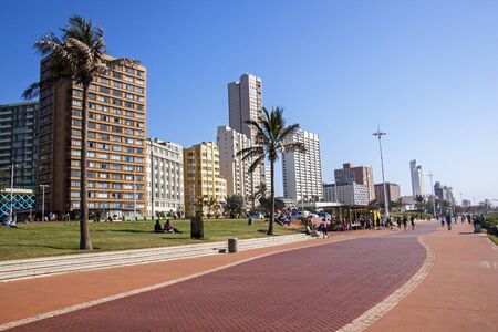 DURBAN, SOUTH AFRICA - JUNE 6, 2015 : Morning view of many unknown people on paved promenade against city skyline on Durban beachfront in South Africaのeditorial素材
